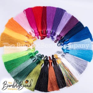May include: A collection of colorful tassels arranged in a circular pattern. The tassels are in various shades, including pink, red, orange, green, blue, and purple. The BumbleBead Company logo is visible at the bottom.