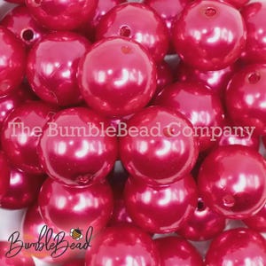 May include: Close-up of a pile of large, shiny, red beads. The beads have a pearl-like finish and are clustered together. The text "The BumbleBead Company" is visible on the beads.