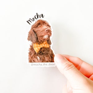 May include: A brown and white dog wearing a yellow bow tie. The dog is looking to the right. The text "mocha" is above the dog and the text "@mocha_the_dood" is below the dog.