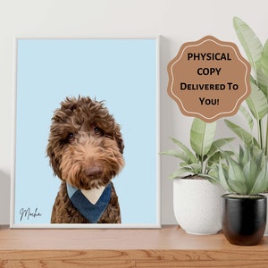 Op de afbeelding: Een ingelijst portret van een bruine Goldendoodle-hond met een blauwe bandana, tegen een lichtblauwe achtergrond. De naam van de hond, Mocha, is cursief geschreven. Een sticker luidt: "FYSIEKE KOPIE BIJ U BEZORGD!"