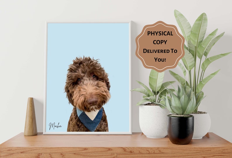 Op de afbeelding: Een ingelijst portret van een bruine Goldendoodle-hond met een blauwe bandana, tegen een lichtblauwe achtergrond. De naam van de hond, Mocha, is cursief geschreven. Een sticker luidt: "FYSIEKE KOPIE BIJ U BEZORGD!"