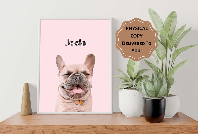 Op de afbeelding: Een ingelijst portret van een lachende Franse Bulldog genaamd Josie, tegen een zachtroze achtergrond. De vacht van de hond is lichtbruin en hij heeft een klein label aan zijn halsband. De tekst "PHYSICAL COPY DELIVERED TO YOU!" staat op een bruin label.