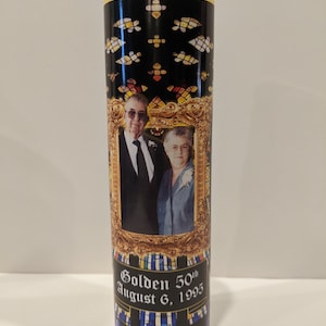 Op de afbeelding: Een glazen kaars met een zwart en gouden ontwerp. De kaars heeft een foto van een stel in een gouden lijst. De tekst "Golden 50th August 6, 1995" staat op de kaars gedrukt.