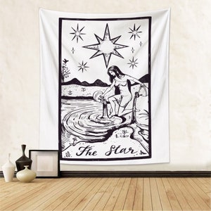May include: Black and white tapestry featuring a tarot card illustration of The Star. The card depicts a woman pouring water from a pitcher into a pool of water, with a large star above her. The text "The Star" is written below the image.