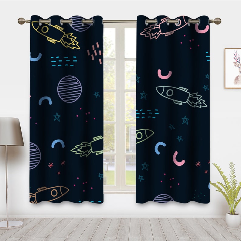 May include: A pair of dark blue curtains with a colorful rocket ship, star, and planet pattern. The curtains have grommets at the top for hanging.