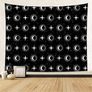 May include: Black tapestry with a repeating pattern of white crescent moons and stars. The tapestry is hanging on a wall with a wooden floor in front of it.