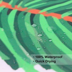 May include: Close-up of a green and orange tropical leaf patterned fabric shower curtain. Water droplets are on the fabric, demonstrating its waterproof and quick-drying features.