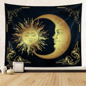 May include: A tapestry featuring a gold sun and crescent moon on a dark blue background. The sun and moon have faces and are surrounded by ornate gold scrollwork.