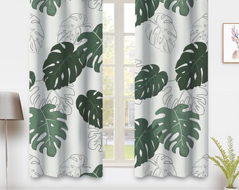 May include: Two green and white patterned curtains with a tropical leaf design. The curtains have grommets for hanging.