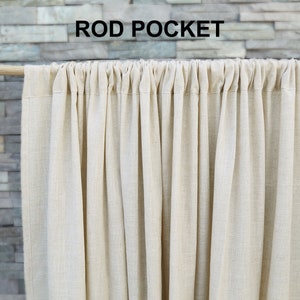 May include: A close-up of the top of a beige curtain with a rod pocket. The curtain is made of a soft, woven fabric.