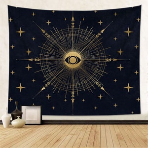 May include: A navy blue tapestry with a gold eye design surrounded by a sunburst pattern and stars.
