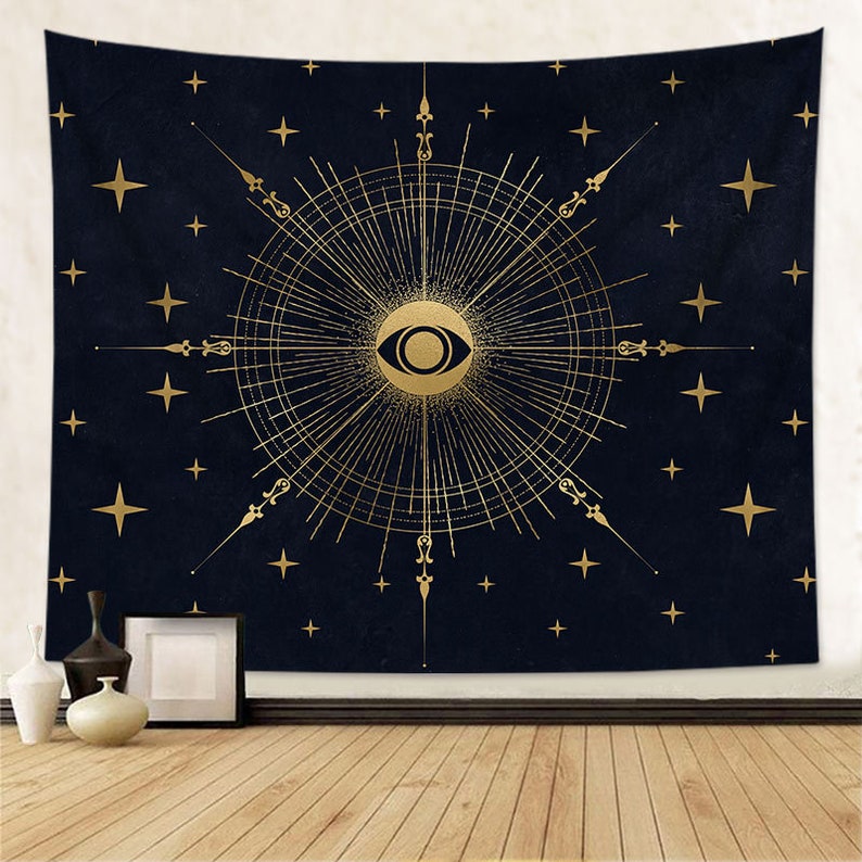 May include: A navy blue tapestry with a gold eye design surrounded by a sunburst pattern and stars.