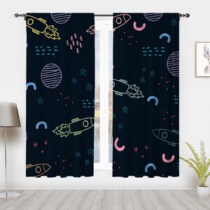 May include: A pair of dark blue curtains with a space-themed pattern. The pattern includes rockets, stars, planets, and geometric shapes in various colors, including pink, blue, yellow, and green.