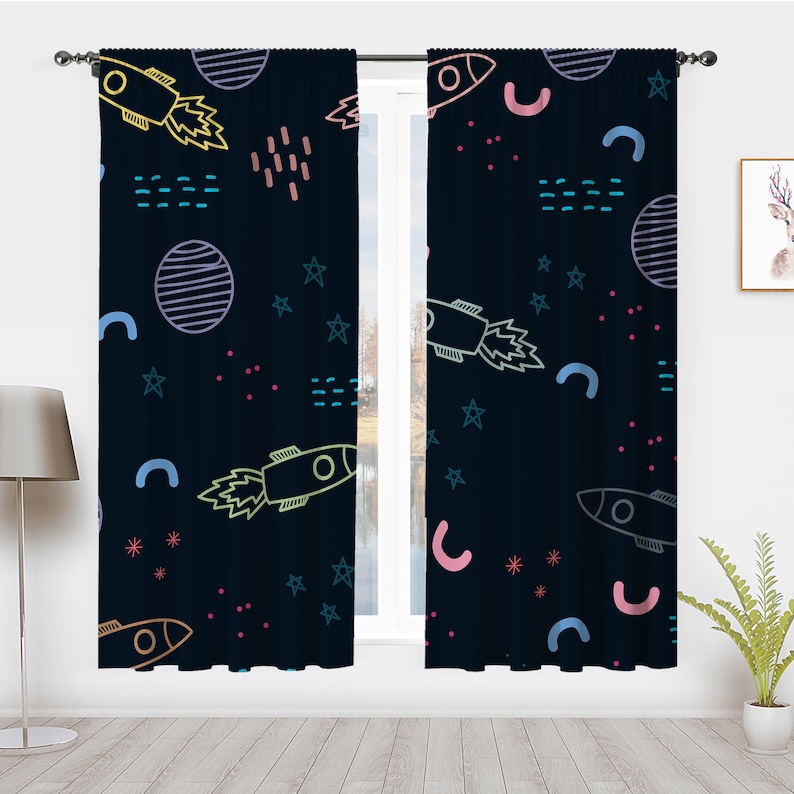 May include: A pair of dark blue curtains with a space-themed pattern. The pattern includes rockets, stars, planets, and geometric shapes in various colors, including pink, blue, yellow, and green.