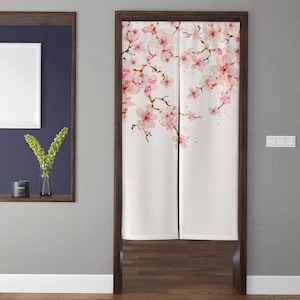 May include: A white fabric room divider with a watercolor print of pink cherry blossoms. The divider is hung on a wooden door frame.