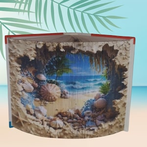 May include: A folded book with a beach scene carved into the pages. The artwork depicts a sandy beach, seashells, and ocean waves. The book's edges are red, and the background is a gradient of blue and tan.