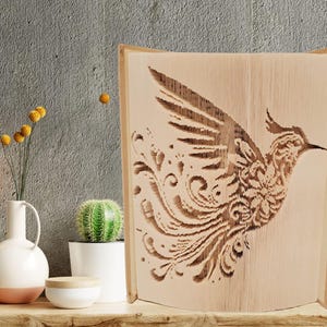 May include: A wooden art piece featuring a detailed carving of a bird in flight. The bird has intricate wing and body patterns, with decorative swirls. The artwork is displayed on a wooden frame, showcasing the natural wood grain.