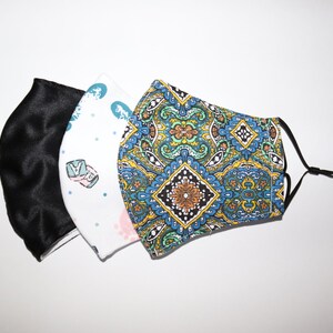 May include: Three fabric face masks. One is black, one is white with a blue and green pattern, and one is blue with a yellow, green, and orange paisley pattern.