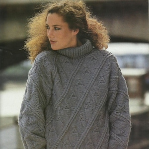 May include: A gray, oversized turtleneck sweater with a textured knit pattern. The sweater features diagonal cable knit detailing and small triangle patterns. The sleeves are long and the collar is ribbed.