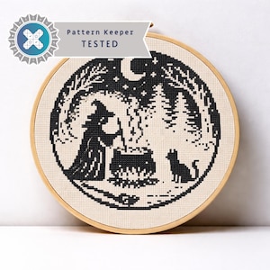 May include: Cross-stitch embroidery in a wooden hoop. The design features a witch stirring a cauldron, a black cat, and a forest scene under a crescent moon and stars. The text "Pattern Keeper TESTED" is displayed.
