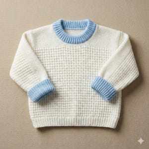May include: A cream-coloured knitted sweater with a waffle-like texture on the body and ribbed sleeves. The collar and cuffs are light blue. The sweater is designed for a child.