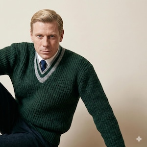 May include: A dark green V-neck sweater with grey and white trim, worn over a white shirt and a blue tie. The person is wearing dark blue trousers. The sweater has a ribbed texture.