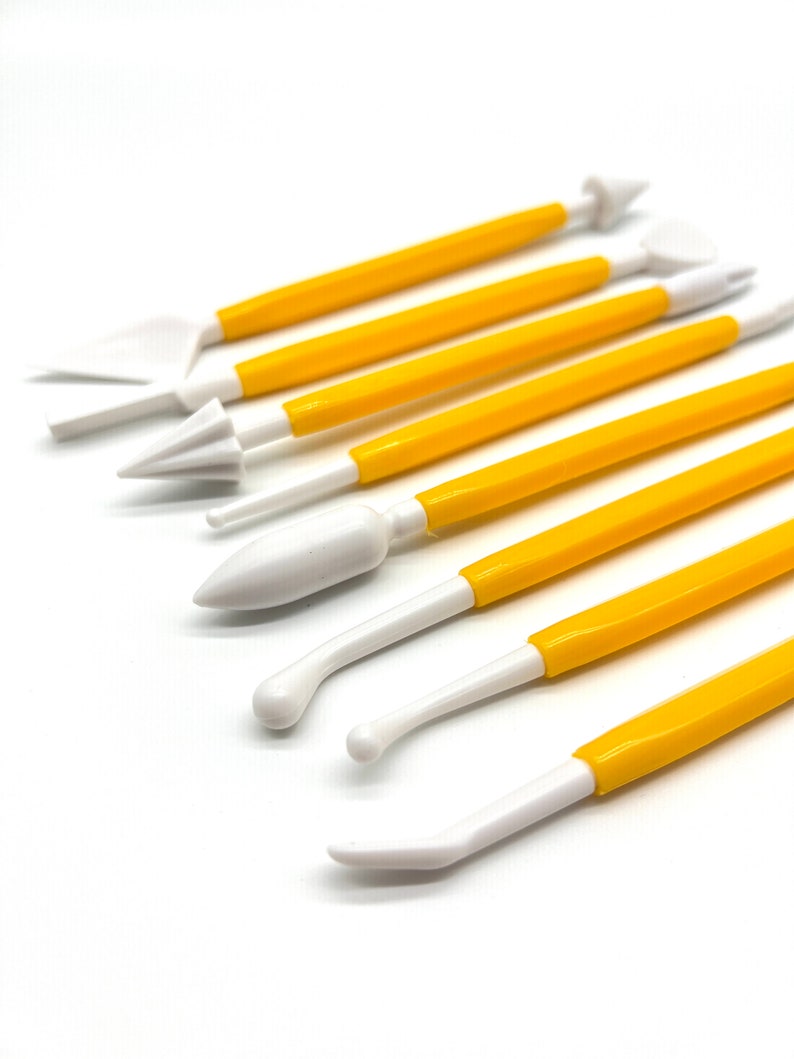 May include: A set of nine yellow and white plastic tools for sculpting and decorating fondant or gum paste. The tools have different shapes and sizes for creating various designs.