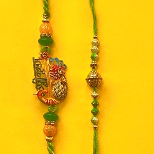 A Pair of Beautiful Sri Krishna  Peacock charm Rakhi and Beaded Rakhi with Complimentary Kumkum Chawal and handwritten Rakshabandhan Card.