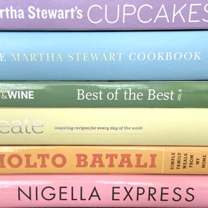 K&ouml;nnte beinhalten: Ein Stapel von sechs Kochb&uuml;chern mit bunten Umschl&auml;gen. Das oberste Buch ist lila und sagt "Martha Stewart's Cupcakes". Das zweite Buch ist hellblau und sagt "The Martha Stewart Cookbook". Das dritte Buch ist gr&uuml;n und sagt "Food & Wine Best of the Best Vol. 8". Das vierte Buch ist gelb und sagt "create inspiring recipes for every day of the week". Das f&uuml;nfte Buch ist orange und sagt "Molto Batali Simple Family Meals From My Home to Yours". Das unterste Buch ist rosa und sagt "Nigella Express".