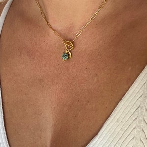 May include: A gold chain necklace with a toggle clasp and a green stone pendant.