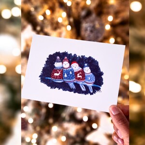4 oiseaux bien au chaud dans leur pull de Noël, blottis ensemble