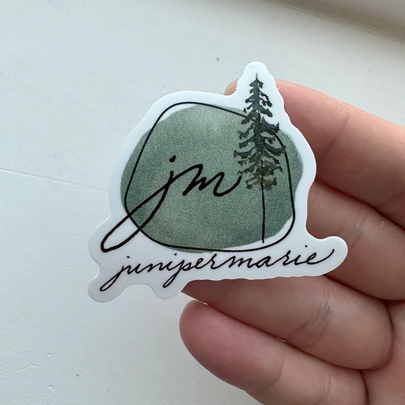 May include: A green watercolour sticker with a stylised "jm" and a small pine tree. The text "junipermarie" is written below the watercolour.