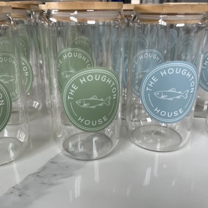 May include: A set of clear glass jars with bamboo lids. Each jar has a sticker with a fish and the text "The Houghton House".