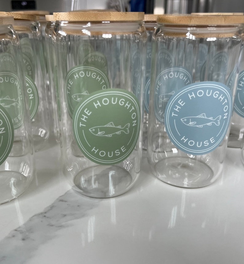 May include: A set of clear glass jars with bamboo lids. Each jar has a sticker with a fish and the text "The Houghton House".