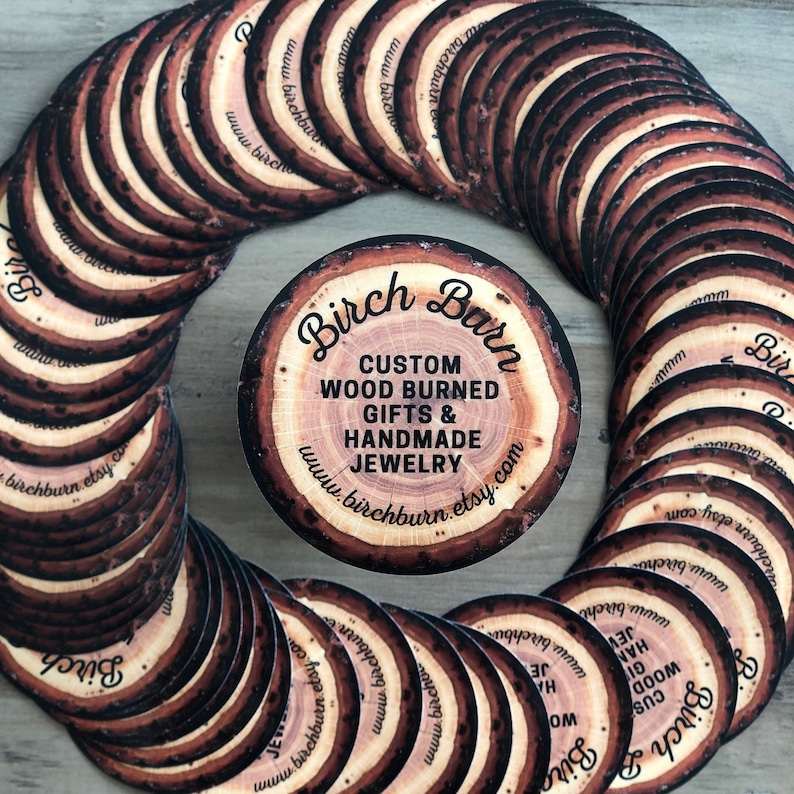 May include: Circular wooden coasters with a wood-burned design, featuring the text "Birch Barn" and "Custom Wood Burned Gifts & Handmade Jewelry." The coasters are arranged in a circular pattern, showcasing a rustic aesthetic.