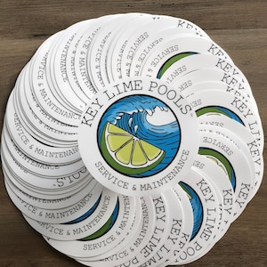May include: A collection of white, circular stickers. Each sticker features the text "KEY LIME POOLS SERVICE & MAINTENANCE" around a central graphic of a lime slice and ocean wave. The stickers are arranged in a fan shape.
