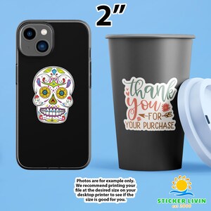 May include: A black smartphone case featuring a colorful sugar skull sticker and a black tumbler with a sticker that reads thank you for your purchase. The text 2 inches is displayed at the top, indicating the size of the stickers shown.