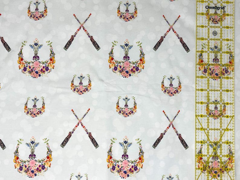 May include: A white fabric featuring a repeating pattern of floral crests and crossed wands. The crests are made of colourful flowers, and the wands have ornate handles. The background has a subtle polka dot design.