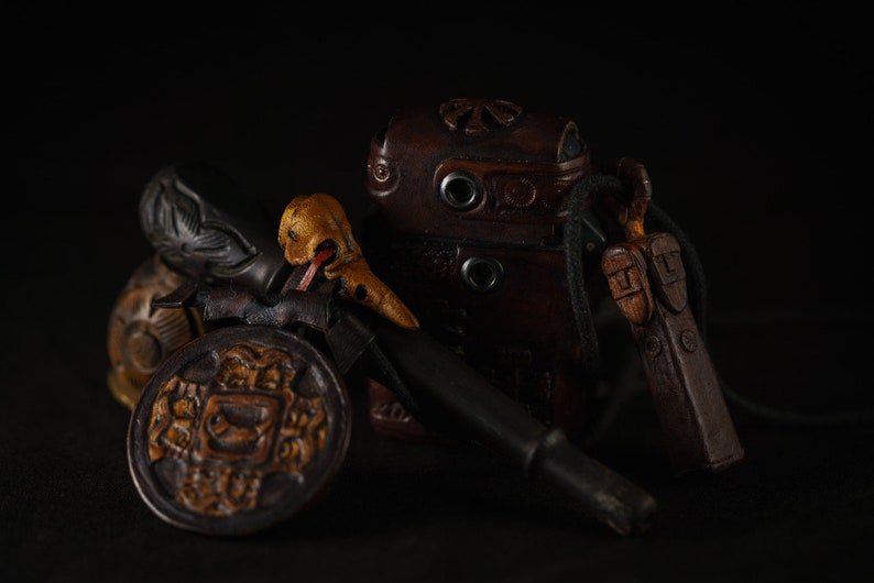 May include: A collection of antique leather goods, including a small pouch, a knife, and a decorative piece with intricate carvings. The items are arranged on a dark background.