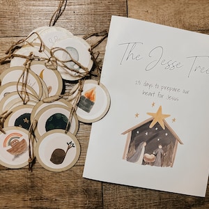 May include: A set of round, illustrated tags with twine and a printed card. The card reads "The Jesse Tree" with text below and a watercolor nativity scene. The tags feature various illustrations, including a rainbow, a tree stump, and a campfire.
