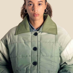 Può includere: Giacca trapuntata verde con colletto verde oliva e grandi bottoni neri. La giacca ha una vestibilità ampia e un sottile effetto sfumato nel tessuto. Lo stile è moderno e casual, adatta a diverse occasioni.