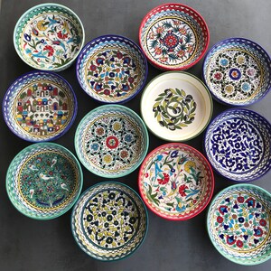 Puede incluir: Una colecci&oacute;n de 10 cuencos de cer&aacute;mica coloridos con intrincados patrones florales y geom&eacute;tricos. Los cuencos son de diferentes tama&ntilde;os y formas, y est&aacute;n dispuestos en c&iacute;rculo sobre una superficie gris.
