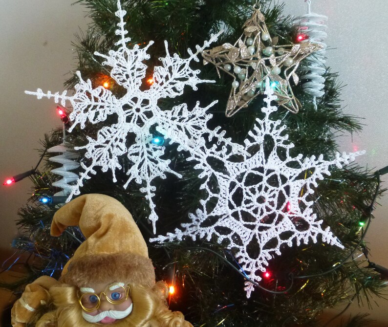 May include: White crocheted snowflakes hanging on a Christmas tree with a gold star ornament and a Santa Claus figurine at the bottom.