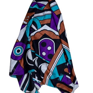 May include: A rectangular scarf featuring a bold geometric pattern in vibrant shades of purple, turquoise, brown, black, and white. The design includes abstract shapes, circles, and lines arranged in a complex, repeating composition across the fabric.