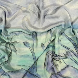 Pode incluir: Um tecido drapeado com um design de paisagem em estilo aquarela. O tecido apresenta um gradiente de cores, passando do azul claro para o verde-azulado e o verde. A paisagem inclui palmeiras, montanhas e um edifício, tudo renderizado em contornos pretos.