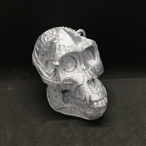 May include: A silver 3D printed skull sculpture of a monkey with intricate details and a mechanical design.