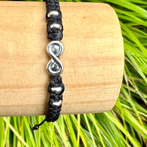 May include: Black braided bracelet with silver infinity charm and silver beads.