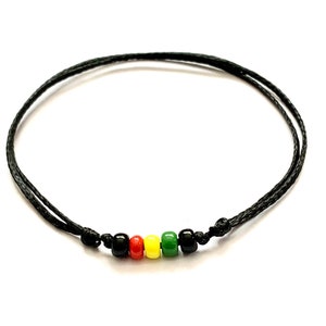 Puede incluir: Un brazalete de cordón negro con cuentas rojas, amarillas y verdes.