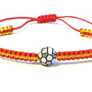 May include: Red and yellow braided bracelet with a white soccer ball charm.