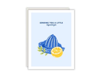 Könnte beinhalten: Eine Grußkarte mit hellblauem Hintergrund, die eine blaue Zitruspresse, eine gelbe Zitronenhälfte und grüne Blätter zeigt. Der Text oben lautet "SENDING YOU A LITTLE squeeze" in dunkelblauer Schrift. Die Karte hat einen weißen Rand.